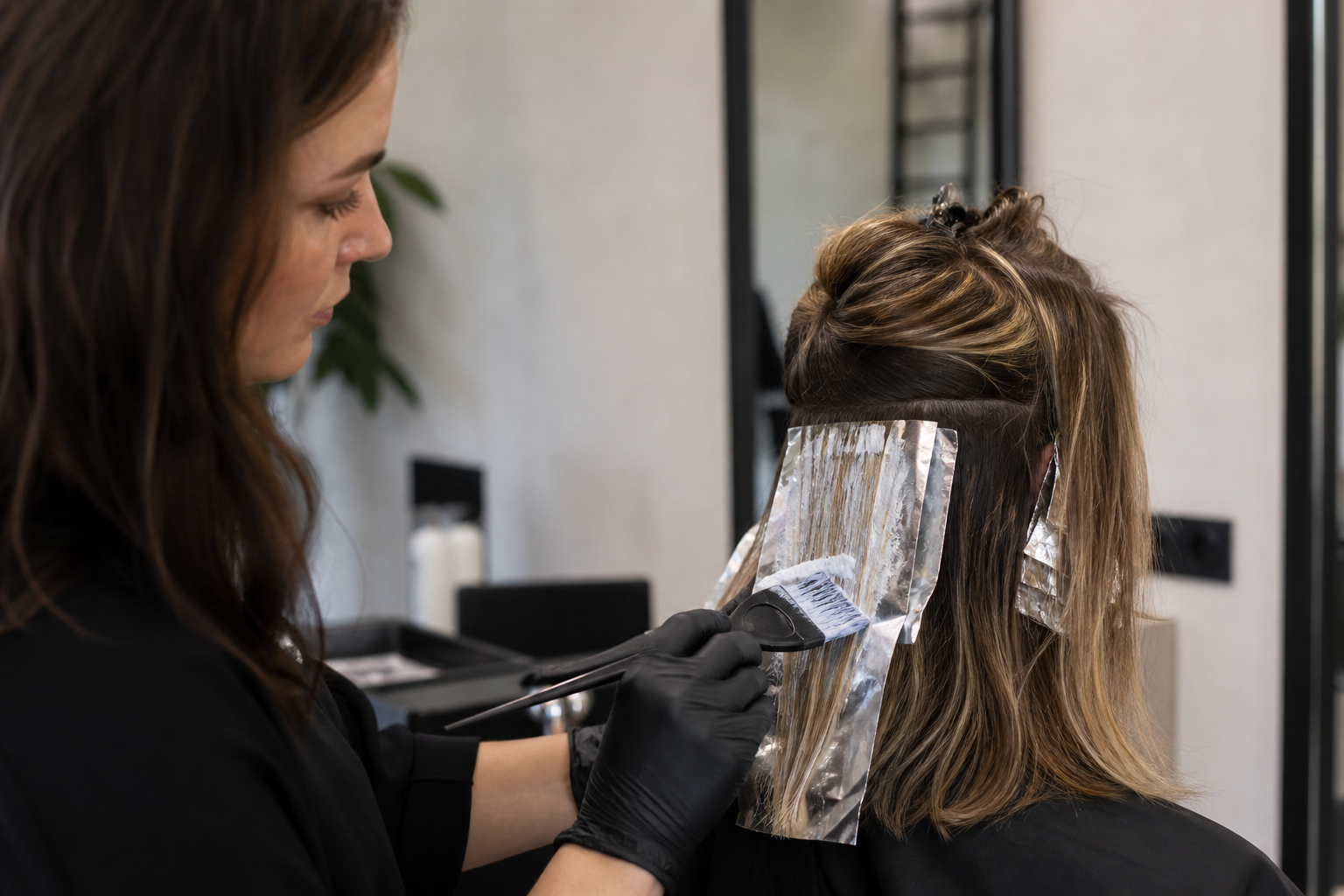 Colorista aplicando balayage con tonos cobre y rubio frio en salon de peluqueria