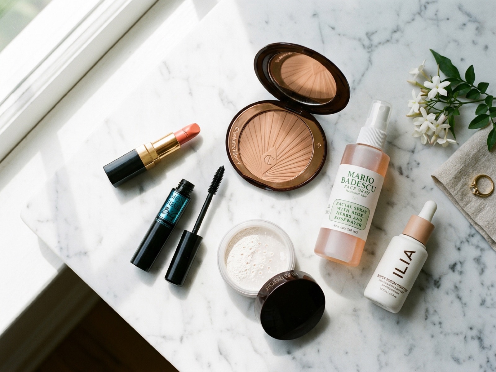 Productos de maquillaje de verano en marmol blanco: bb cream con SPF, polvos fijadores, labial coral, bronzer, rimel waterproof y spray fijador